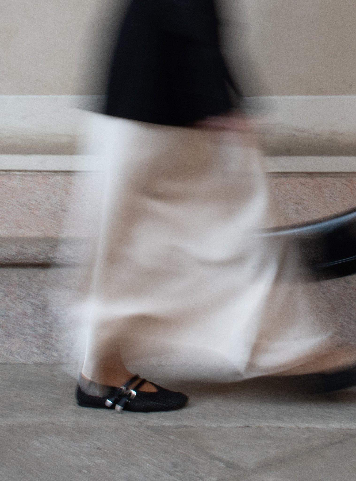 Person in motion wearing a white skirt and black shoes