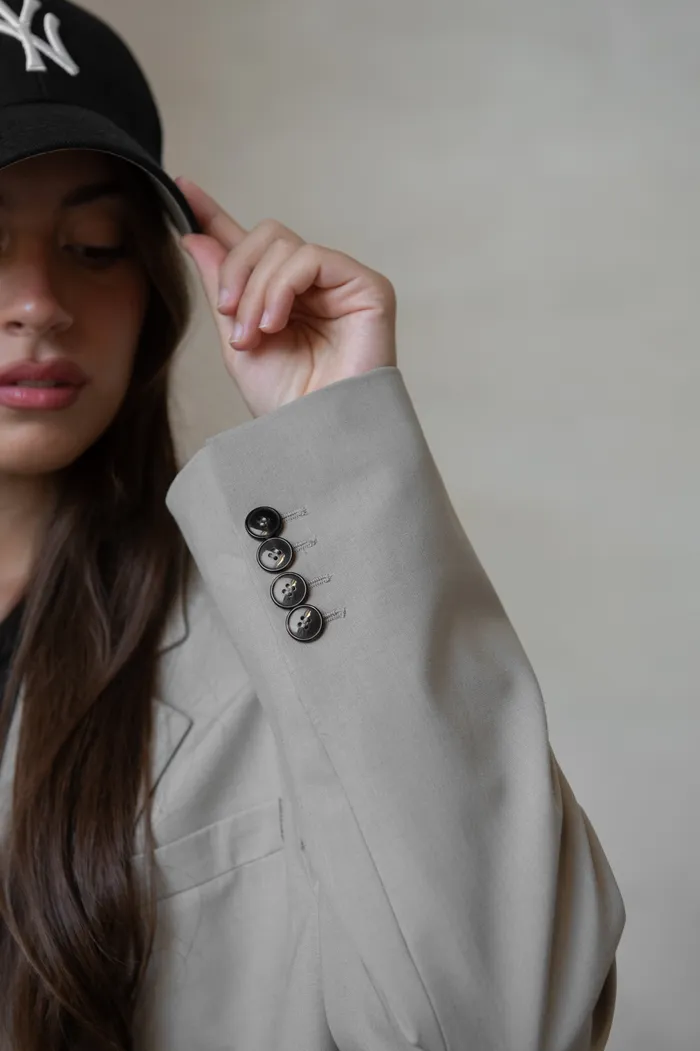 Woman in a cream blazer and black cap